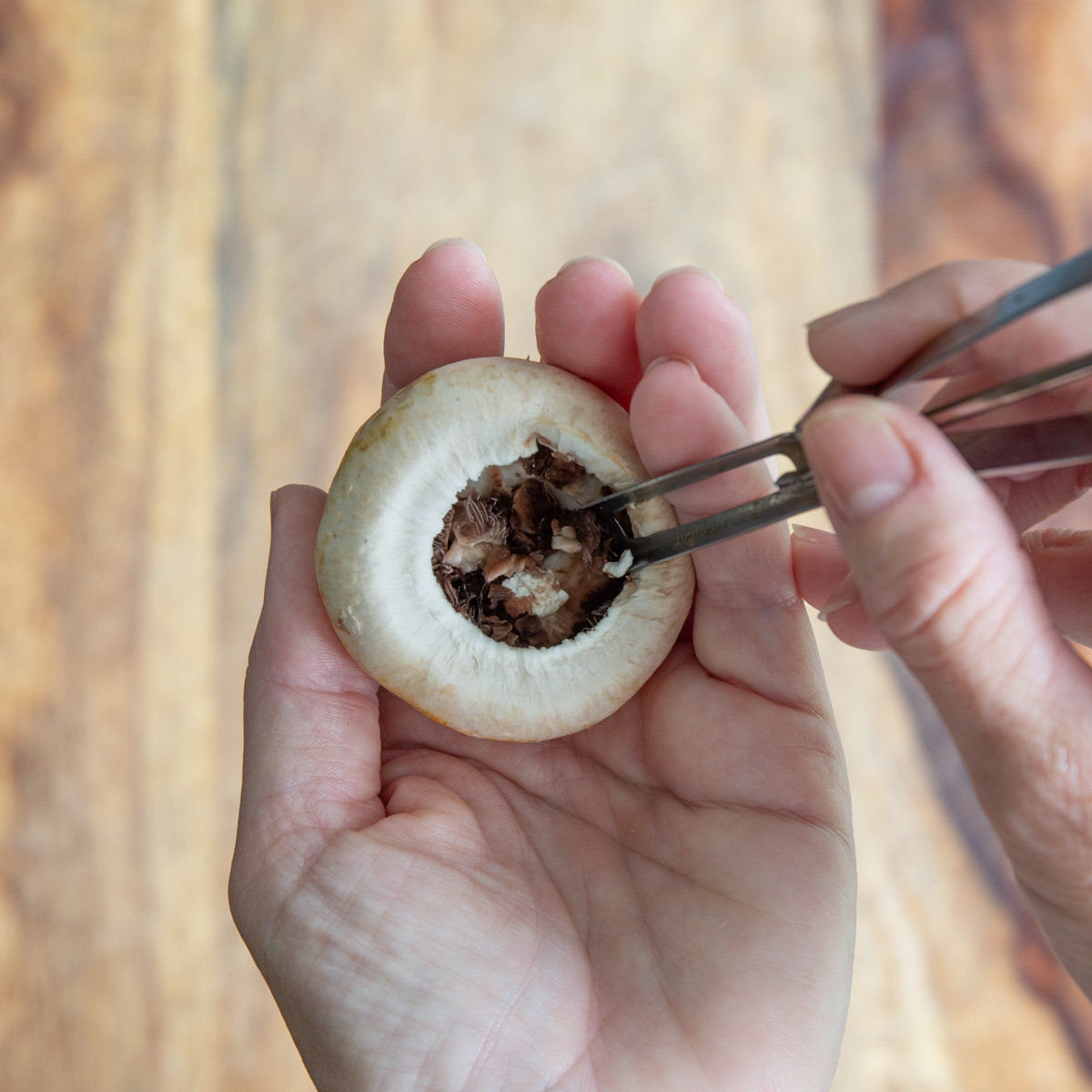 Closeup of removing gills from a mushroom using a potato peeler.