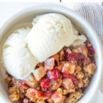 A bowl of apple cranberry crisp and ice cream with overlay text.