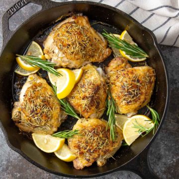 Overhead closeup of lemon rosemary chicken thighs in a skillet.