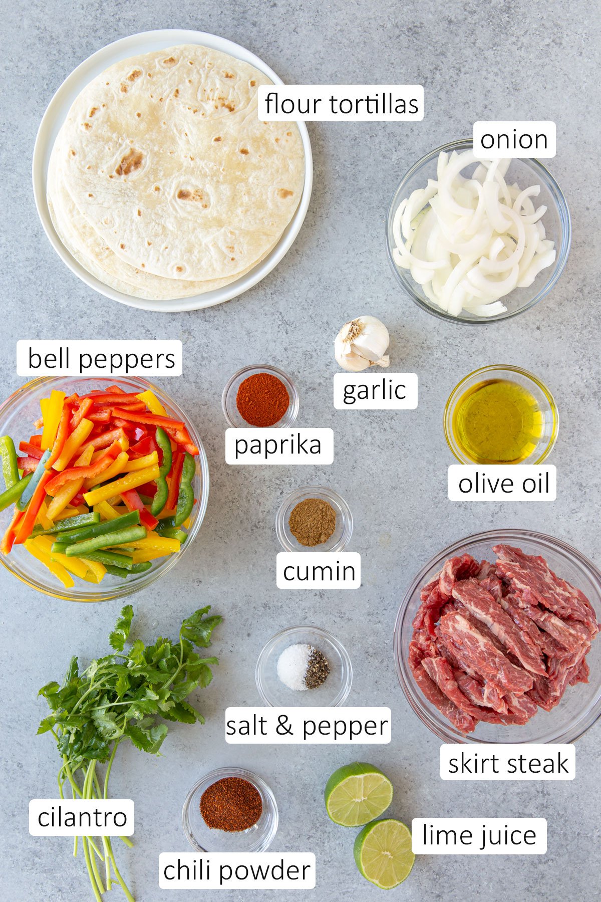 Overhead view of ingredients for fajitas on a gray surface.
