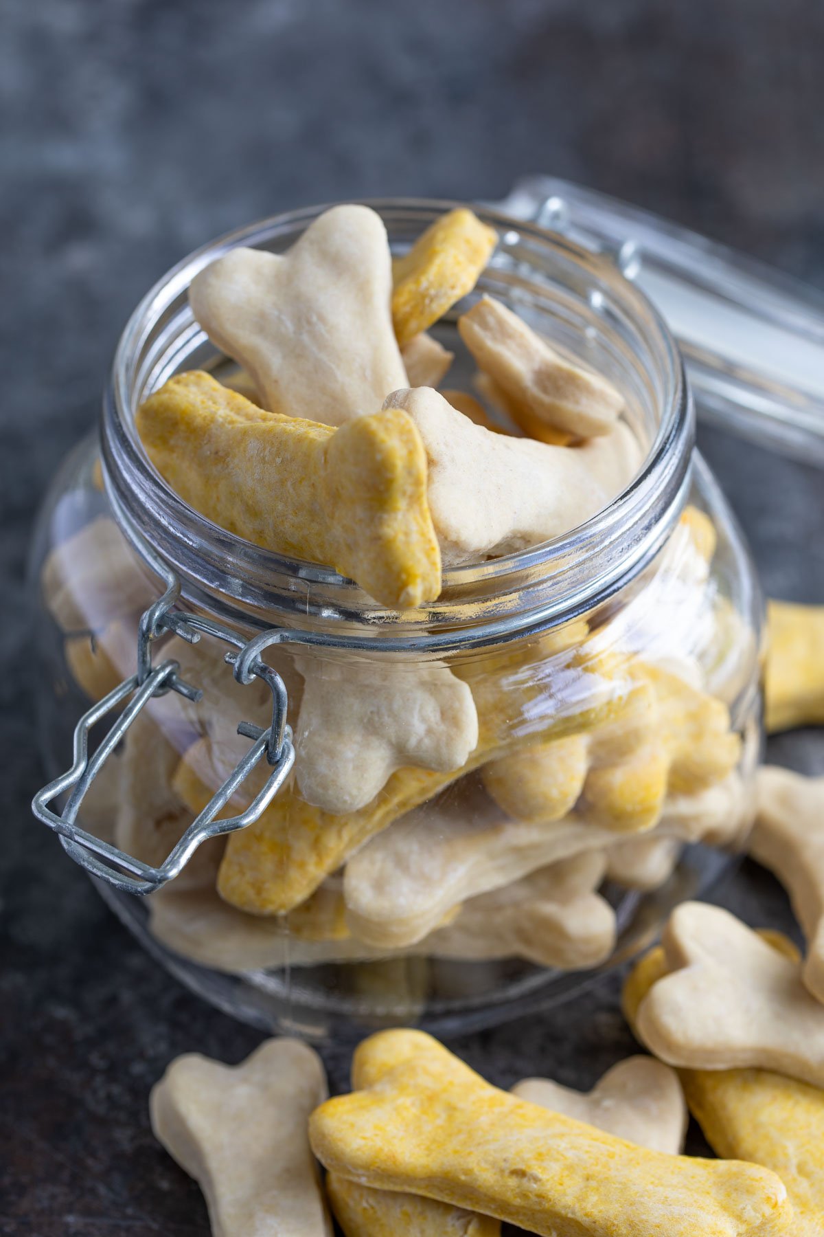 Closeup of bone-shaped homemade dog biscuits in a glass canister.