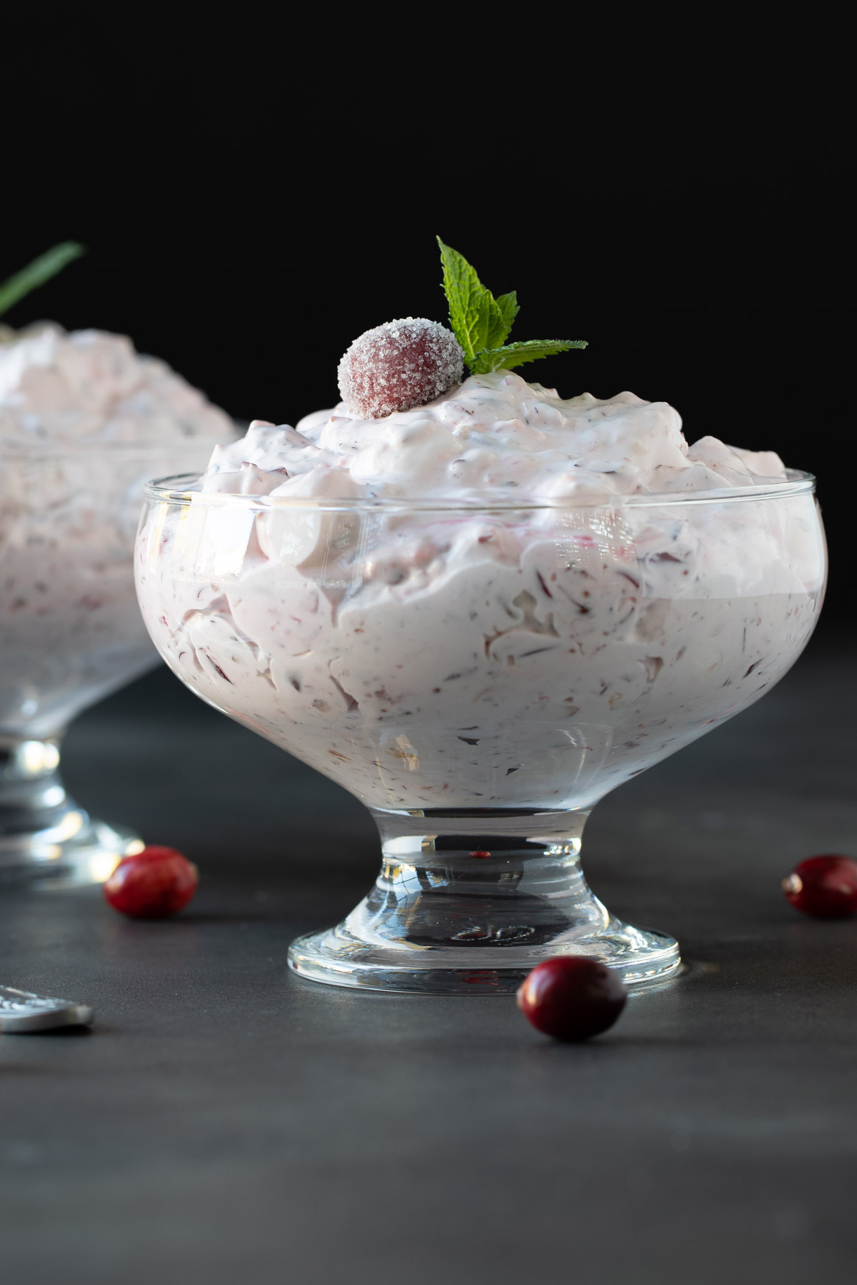 Front view of cranberry fluff salad in a dessert dish garnished with fresh mint.