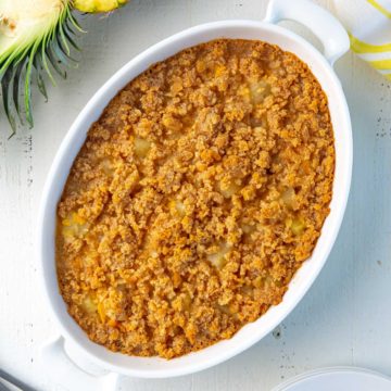 Pineapple and cheese casserole in a white baking dish on a white surface.
