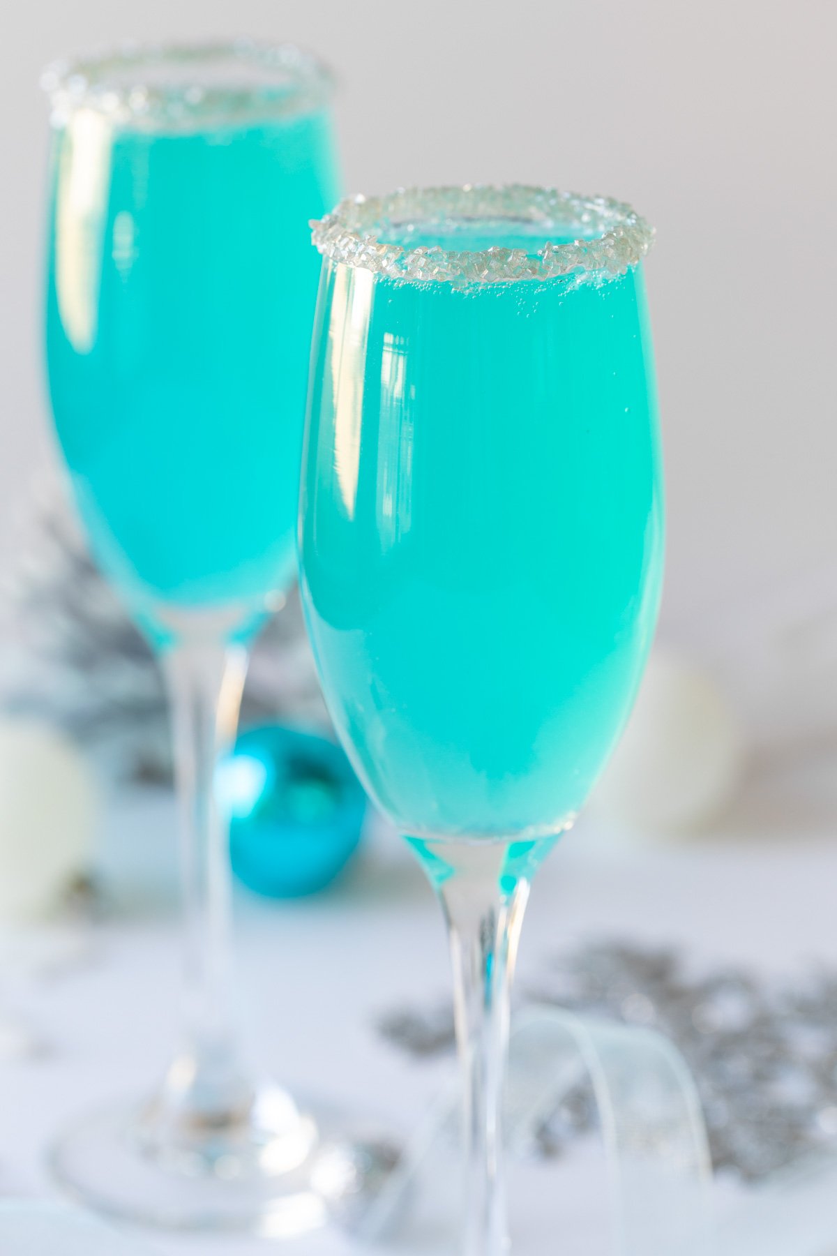 Closeup view of a blue Tiffany mimosa in a champagne flute rimmed with sugar sprinkles.