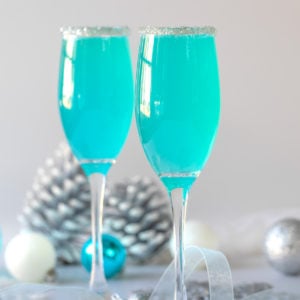 Two Tiffany blue mimosas in champagne flutes rimmed with sugar.