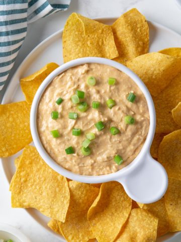Overhead view of a bowl of enchilada dip topped with sliced green onions.