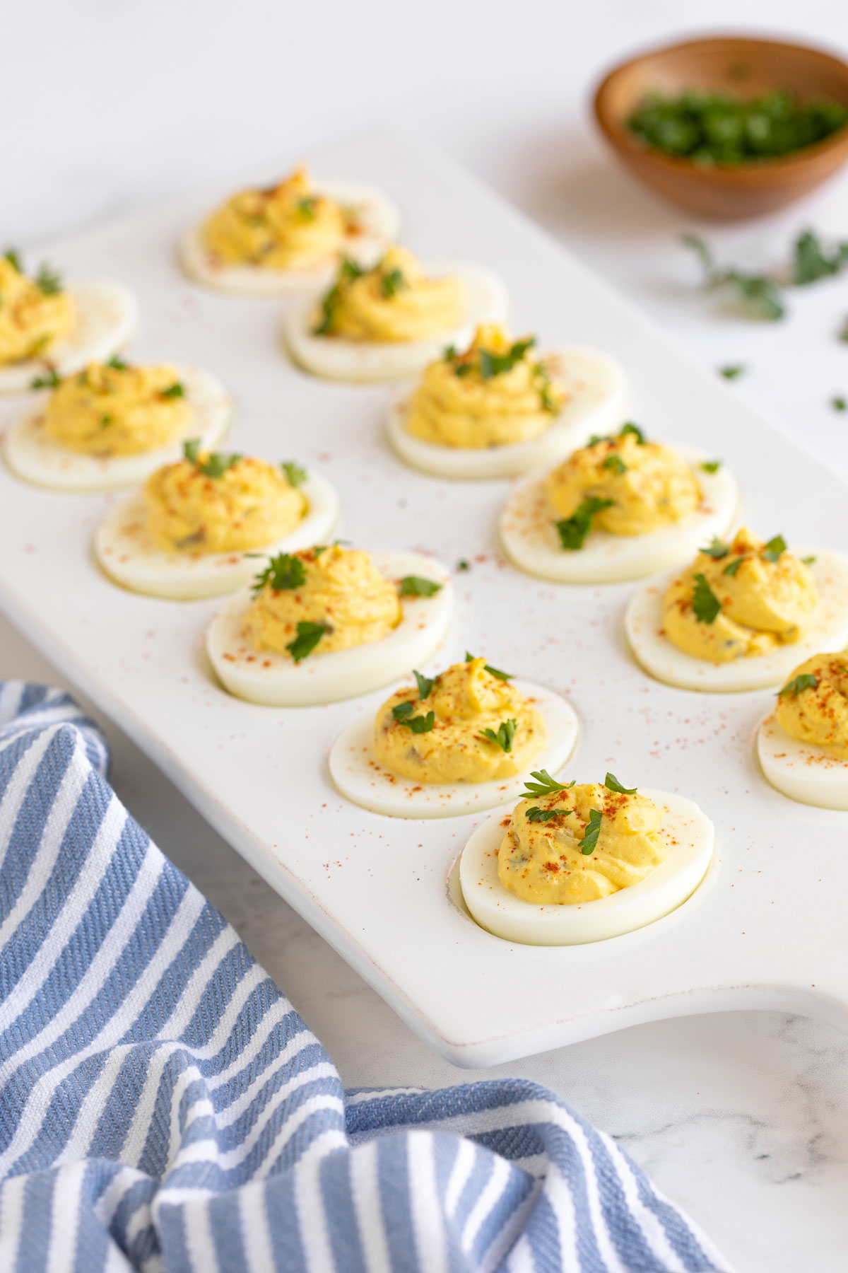Front view of southern deviled eggs on a white platter beside a striped towel.