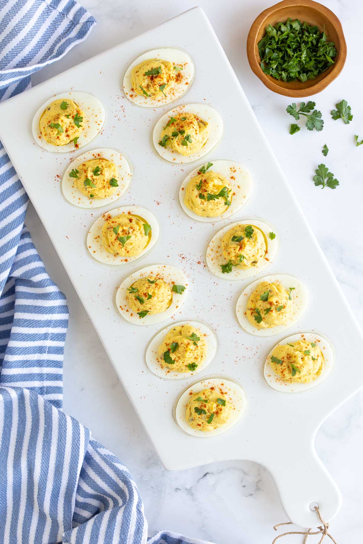 Overhead view of southern deviled eggs on a white platter on a marble surface.