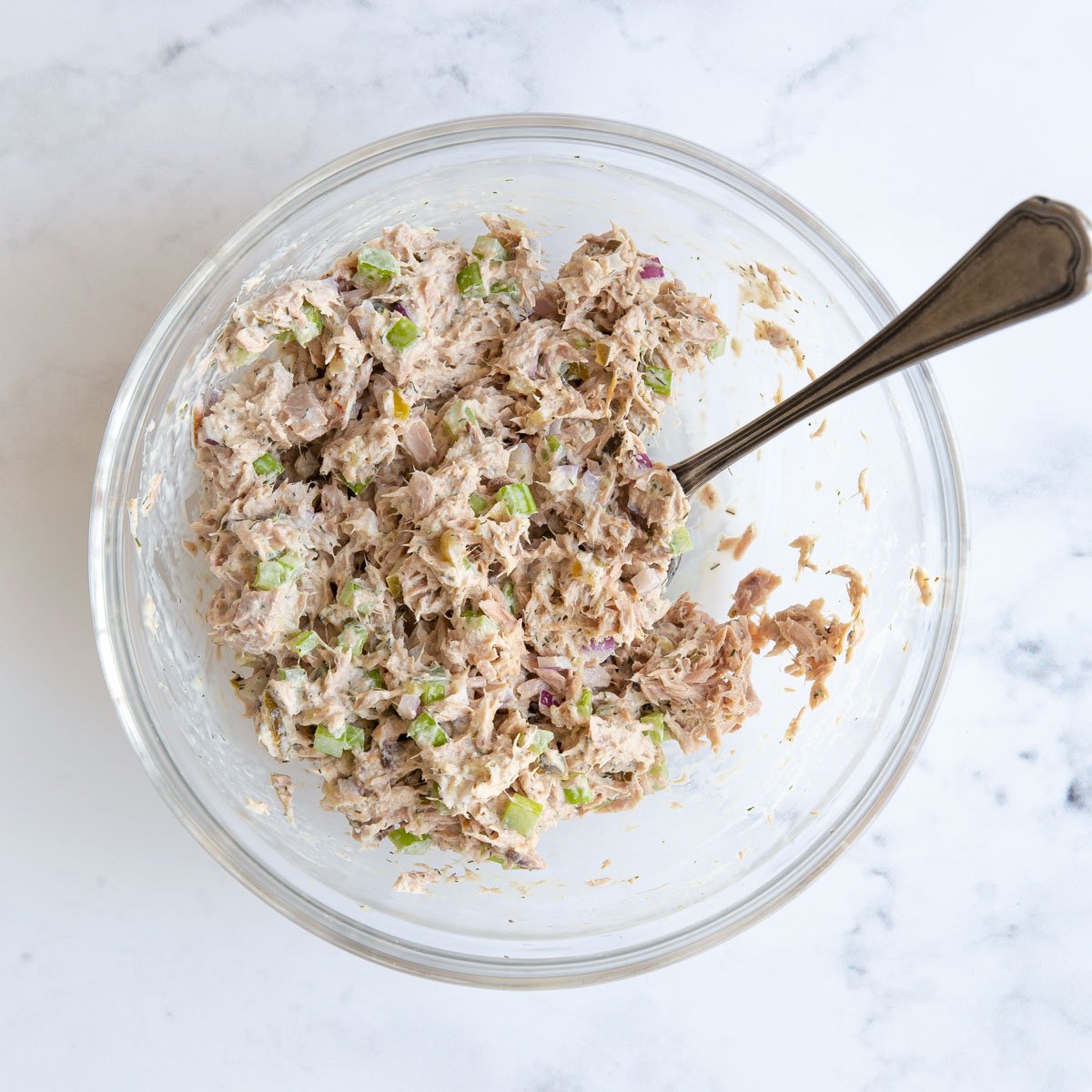Overhead view of tuna fish salad in a bowl with a spoon.
