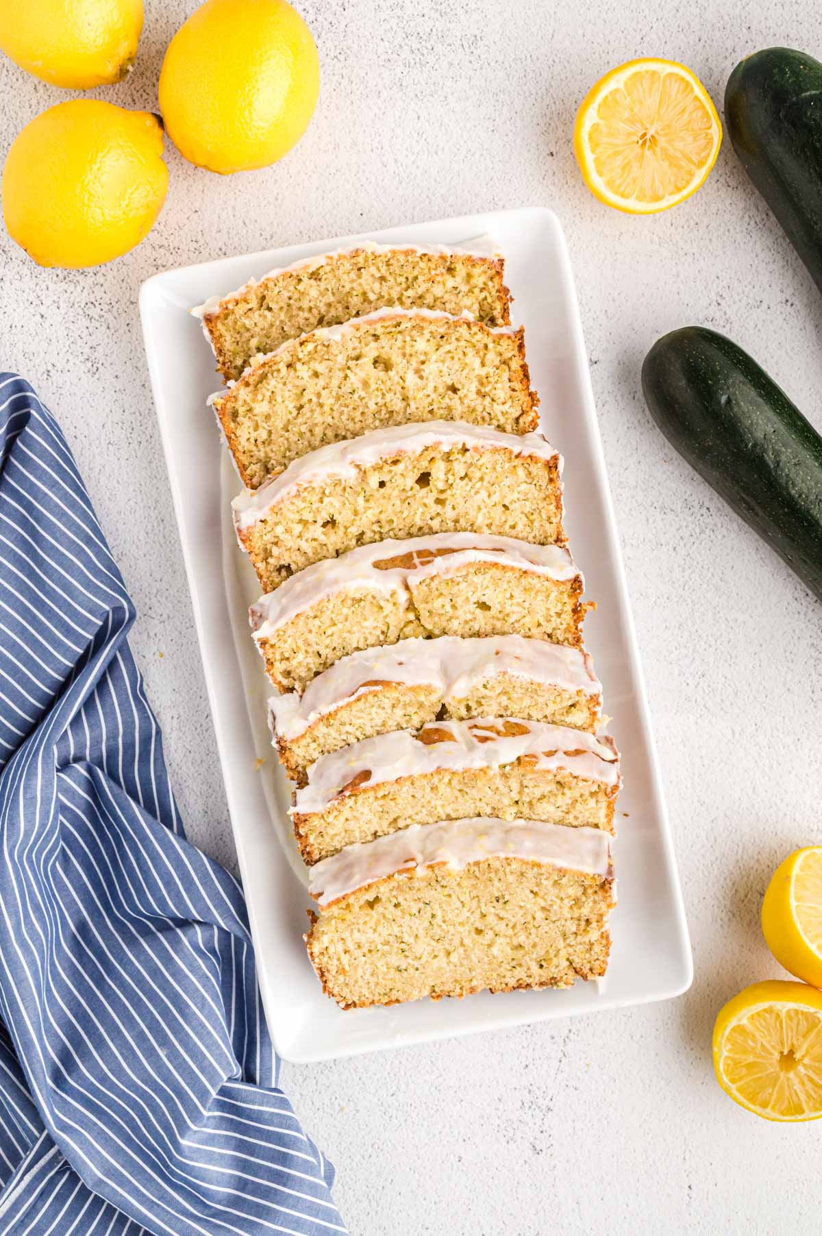 Overhead view of a sliced loaf of zucchini lemon bread on a white platter.