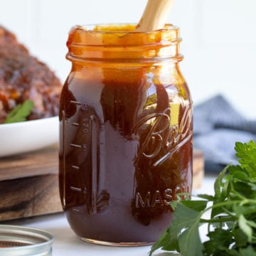Front view of a jar of barbecue sauce with a basting brush.