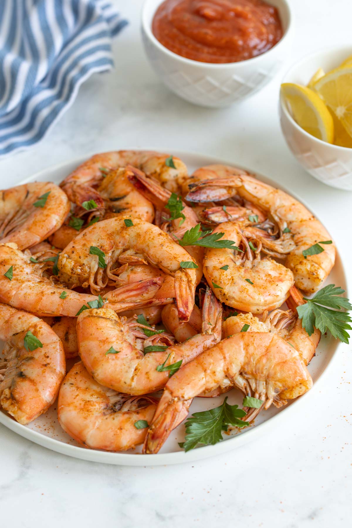 Closeup view of a plate of old bay steamed shrimp sprinkled with parsley.