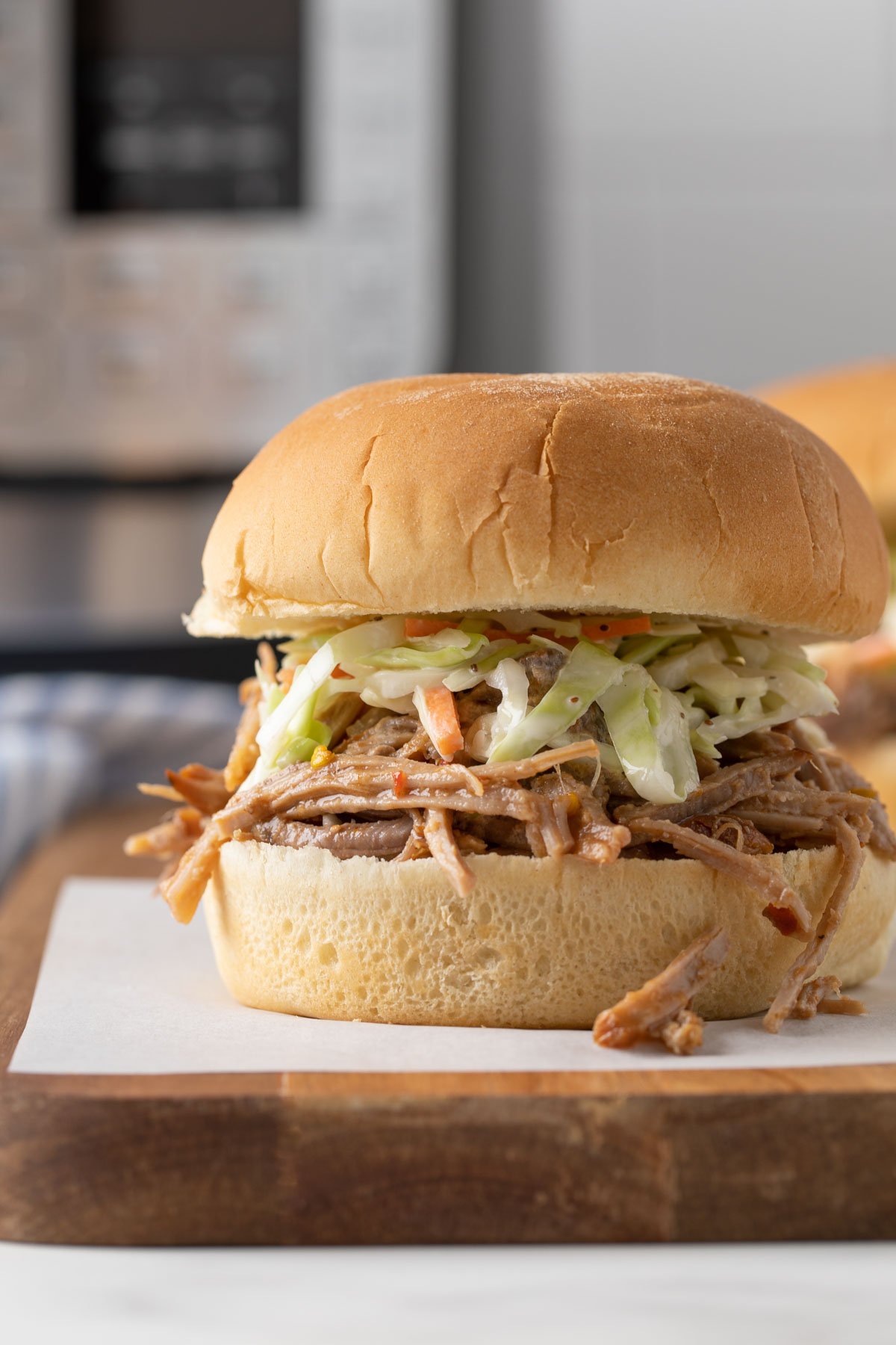 Closeup view of a pulled pork sandwich with an Instant Pot in the background.