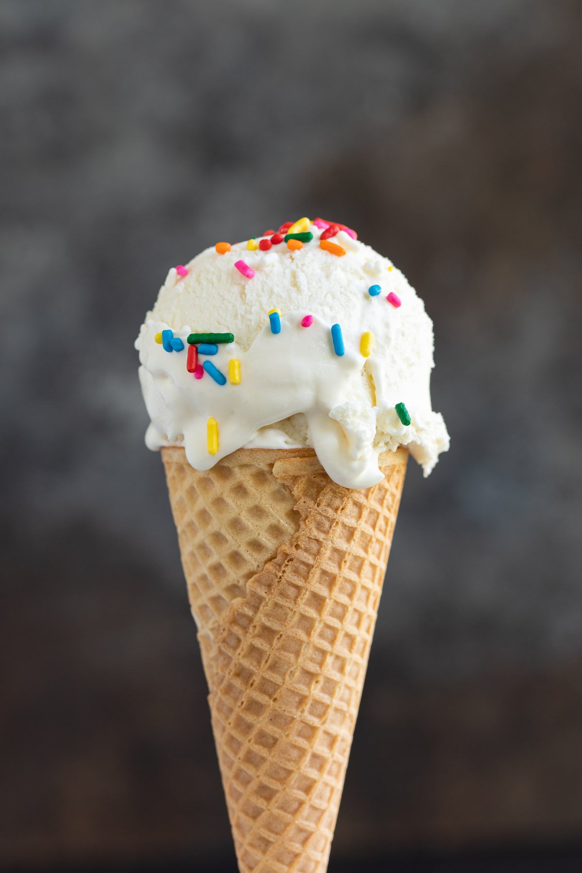A closeup of a vanilla ice cream cone with sprinkles.