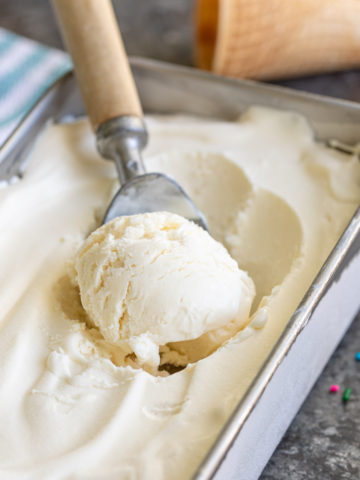 An ice cream scoop in no-churn vanilla ice cream in a metal loaf pan.