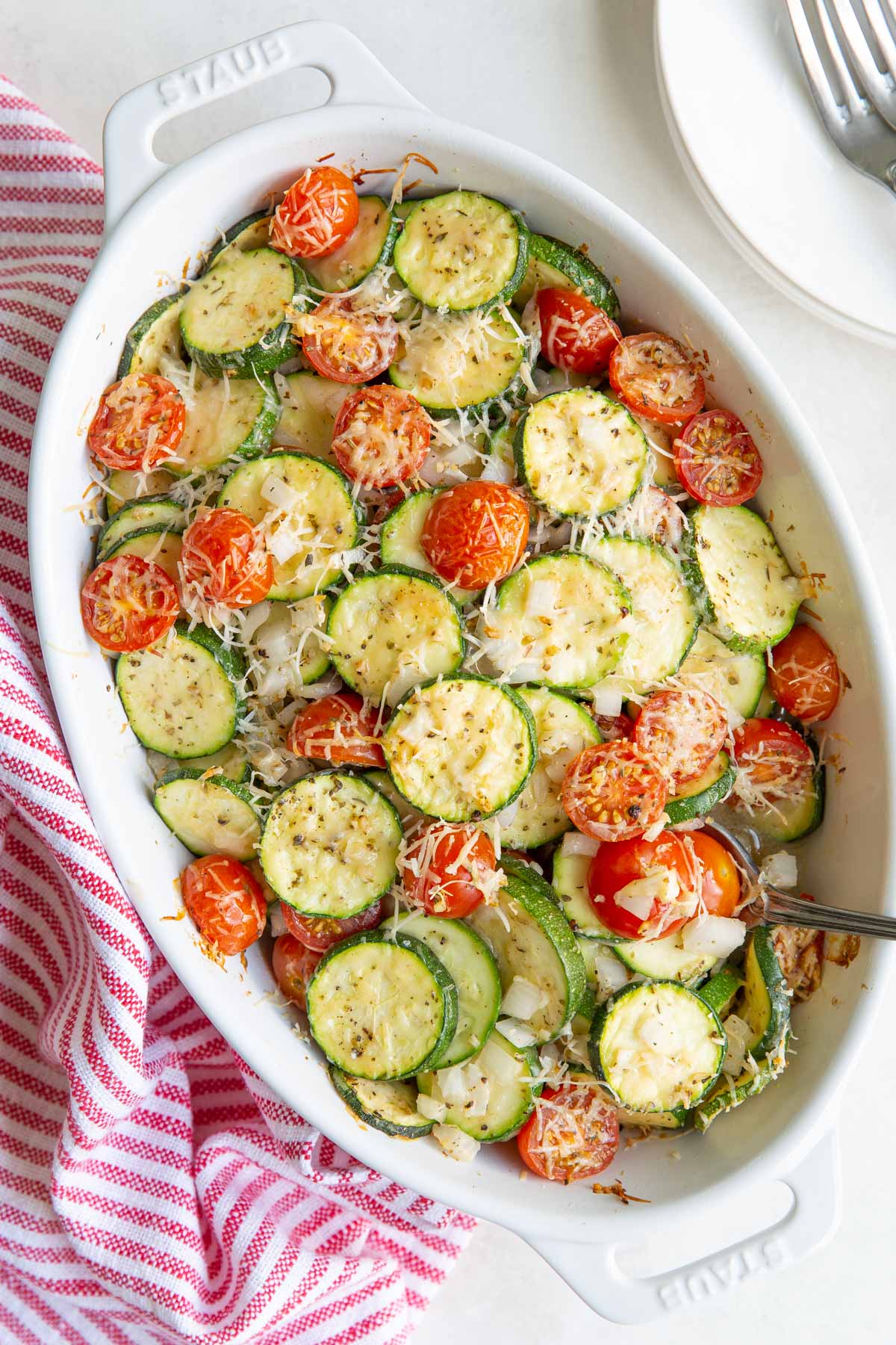 Overhead view of zucchini tomato bake in an oval white baking dish.