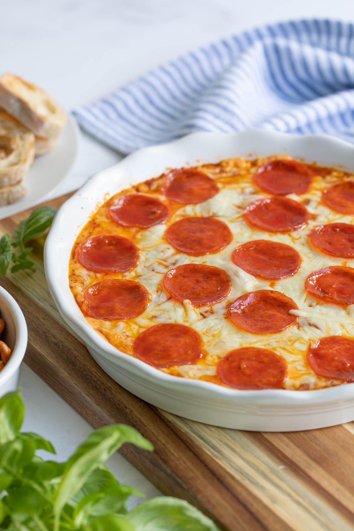 Front view of baked pepperoni pizza dip in a white pie dish.