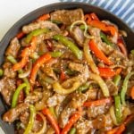 Pepper steak and onions in a skillet with overlay text that says, “Chinese pepper steak”.