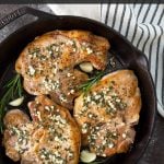 Baked pork chops in a skillet with overlay text that reads, "garlic rosemary pork chops".