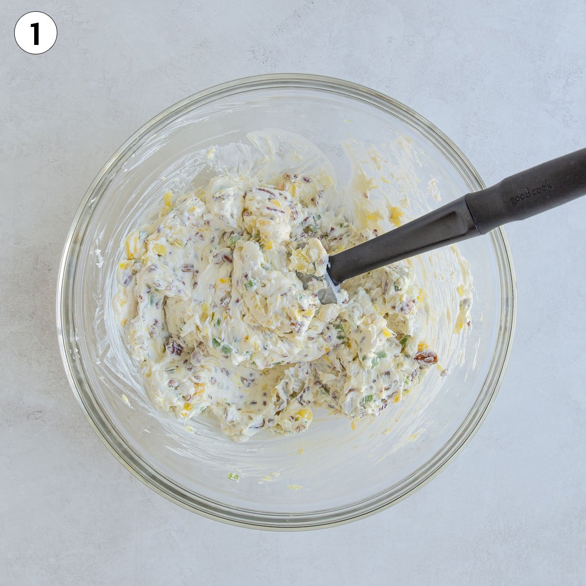 Overhead view of pineapple cream cheese ball mixture in a bowl with a silicone spatula.