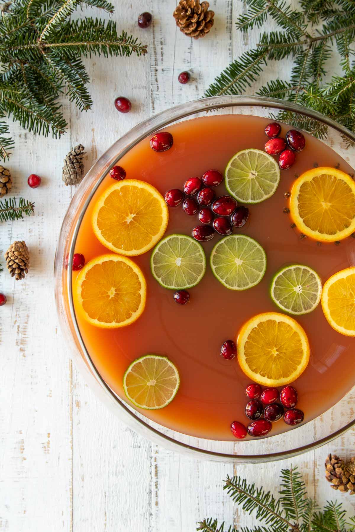 Overhead view of a bowl of Christmas punch garnished with orange, lime and cranberries.
