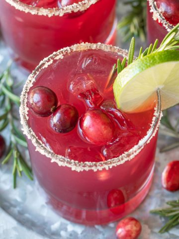 Overhead view of a cranberry margarita garnished with lime, cranberries and rosemary.