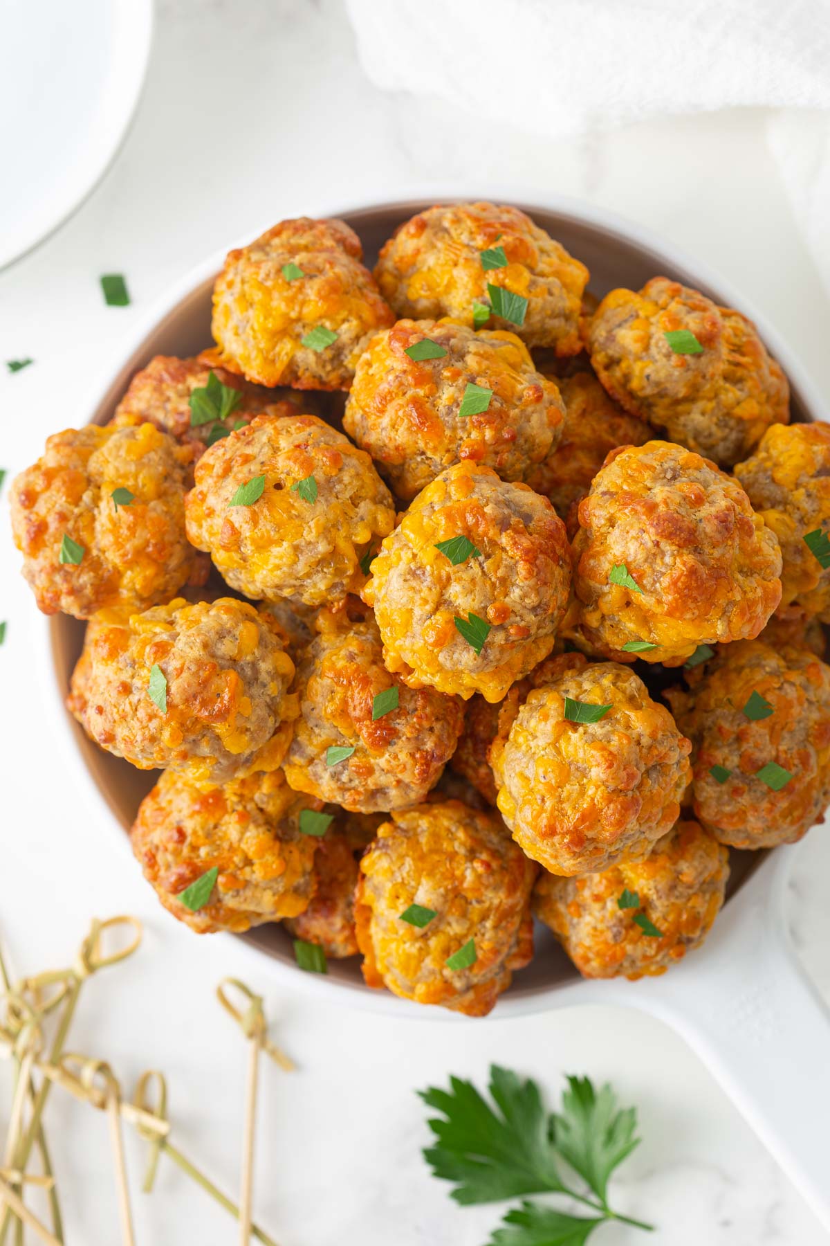 Overhead closeup view of sausage cheese balls in a white serving dish.