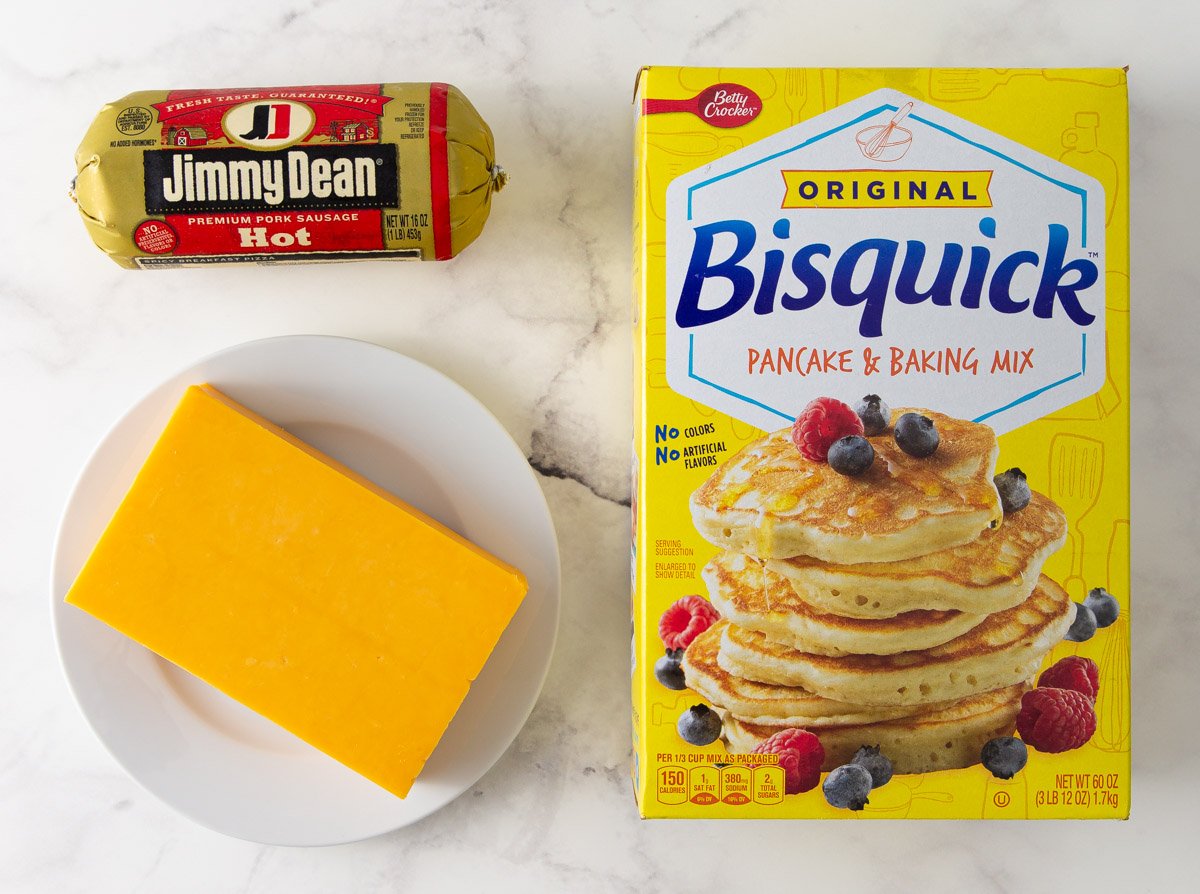 A package of Jimmy Dean hot sausage, a block of cheddar cheese and a box of Bisquick baking mix.