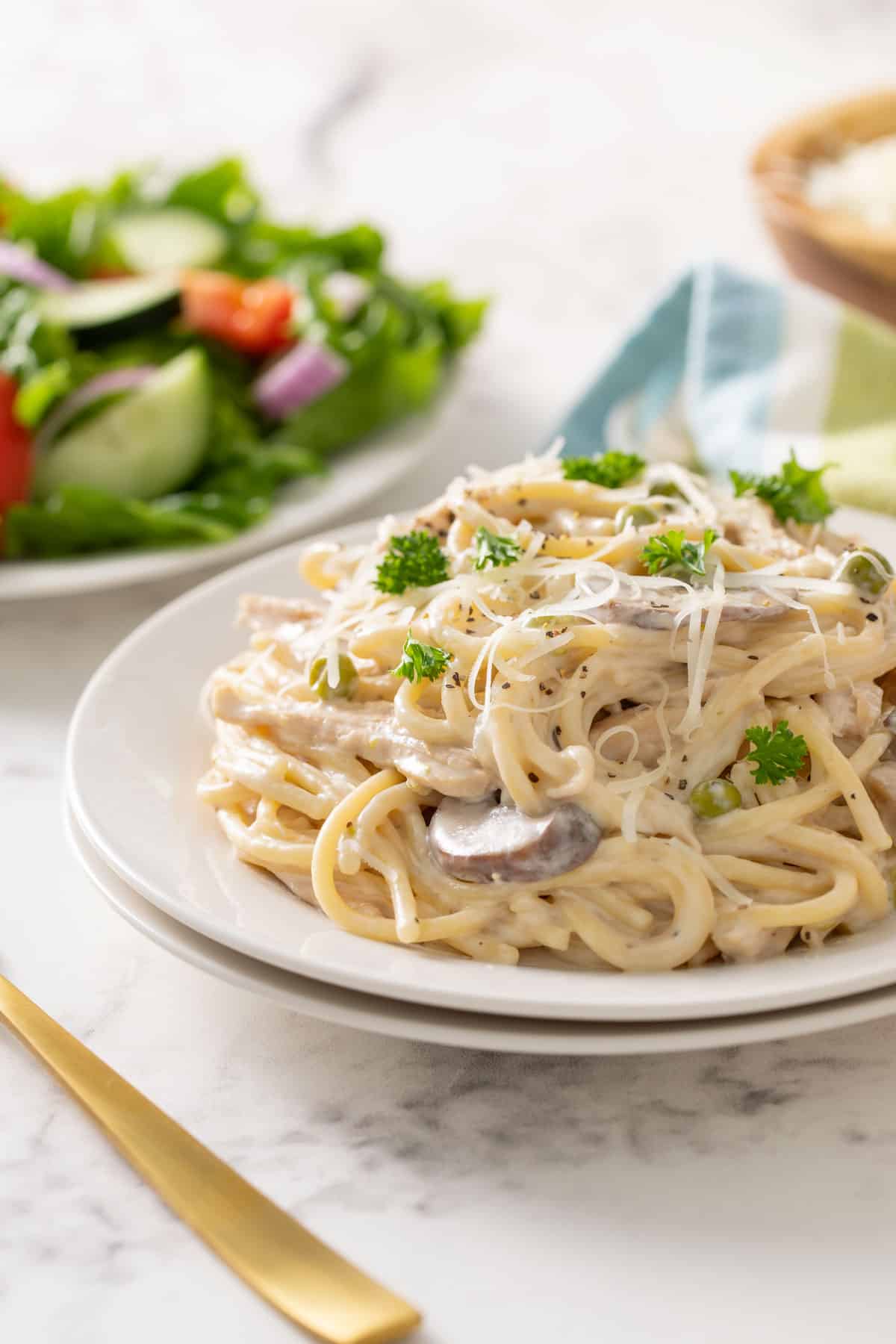 Front view of easy chicken tetrazzini on a white plate by a gold fork.