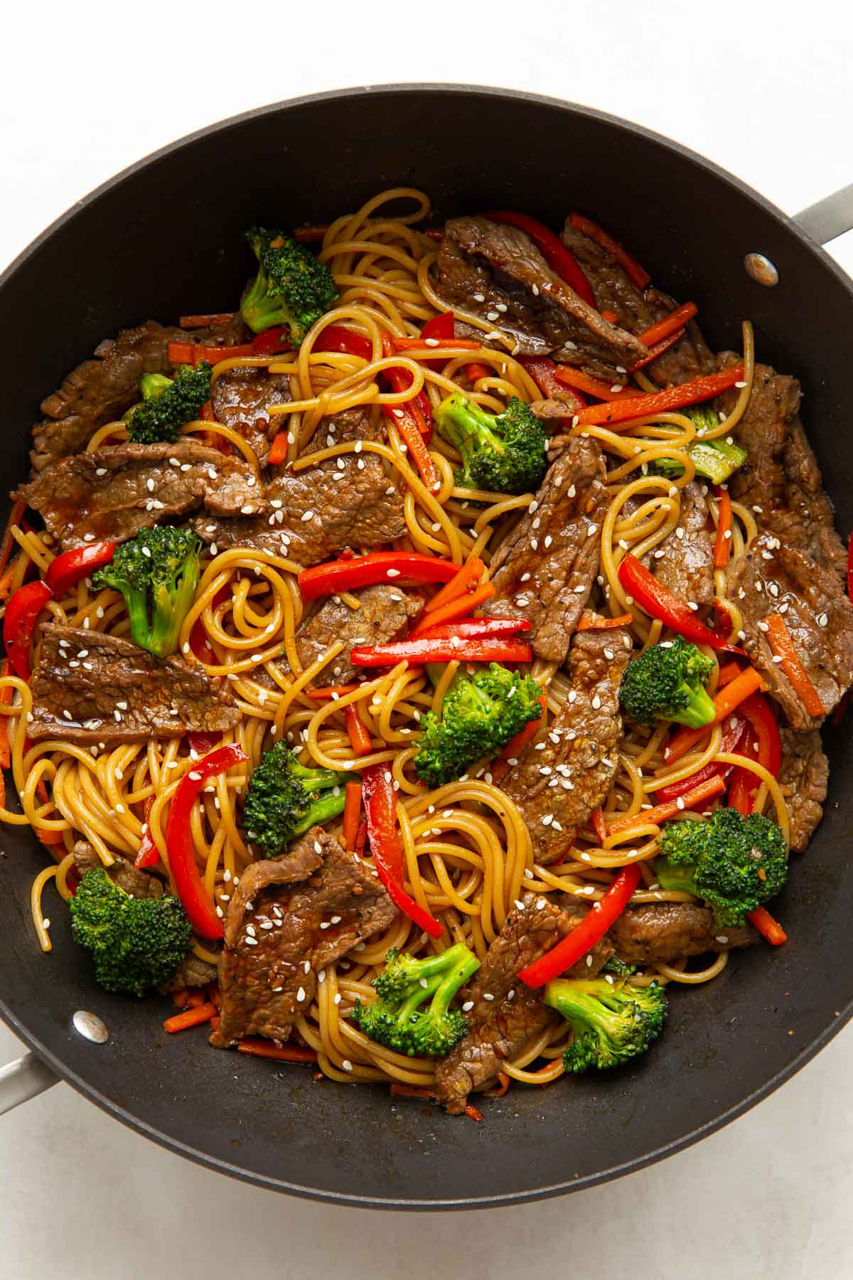 Overhead view of beef and broccoli lo mein in a large skillet.
