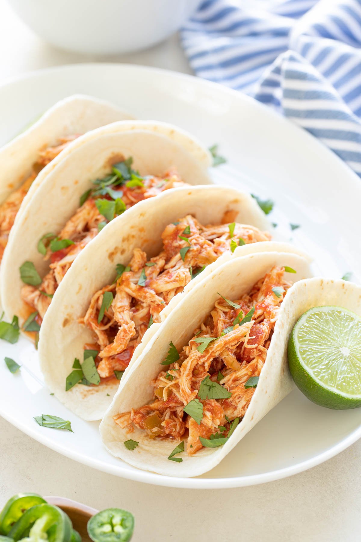 Closeup view of shredded salsa chicken tacos on a white serving platter.