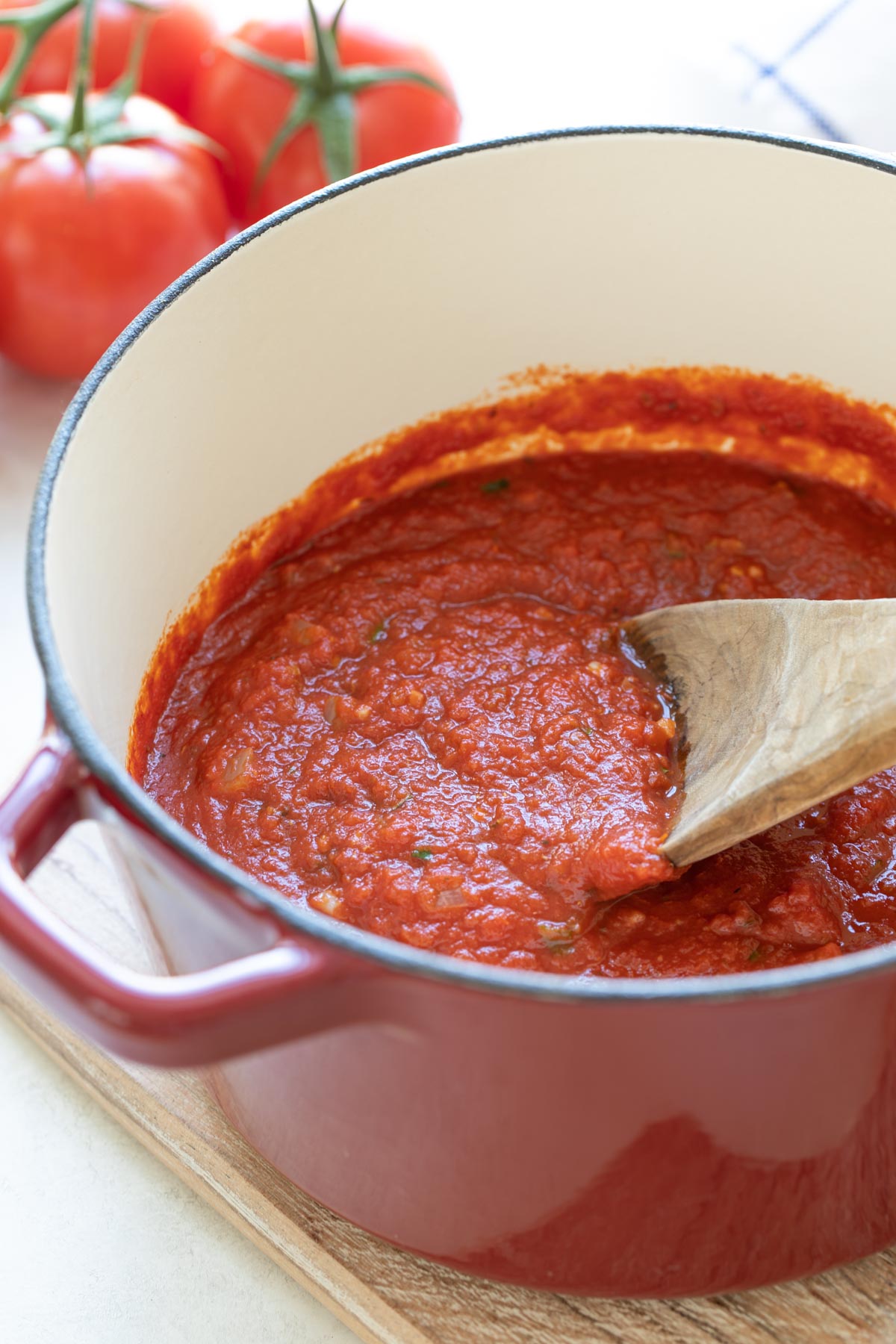 Front view of a wooden spoon in a pot of marinara sauce.