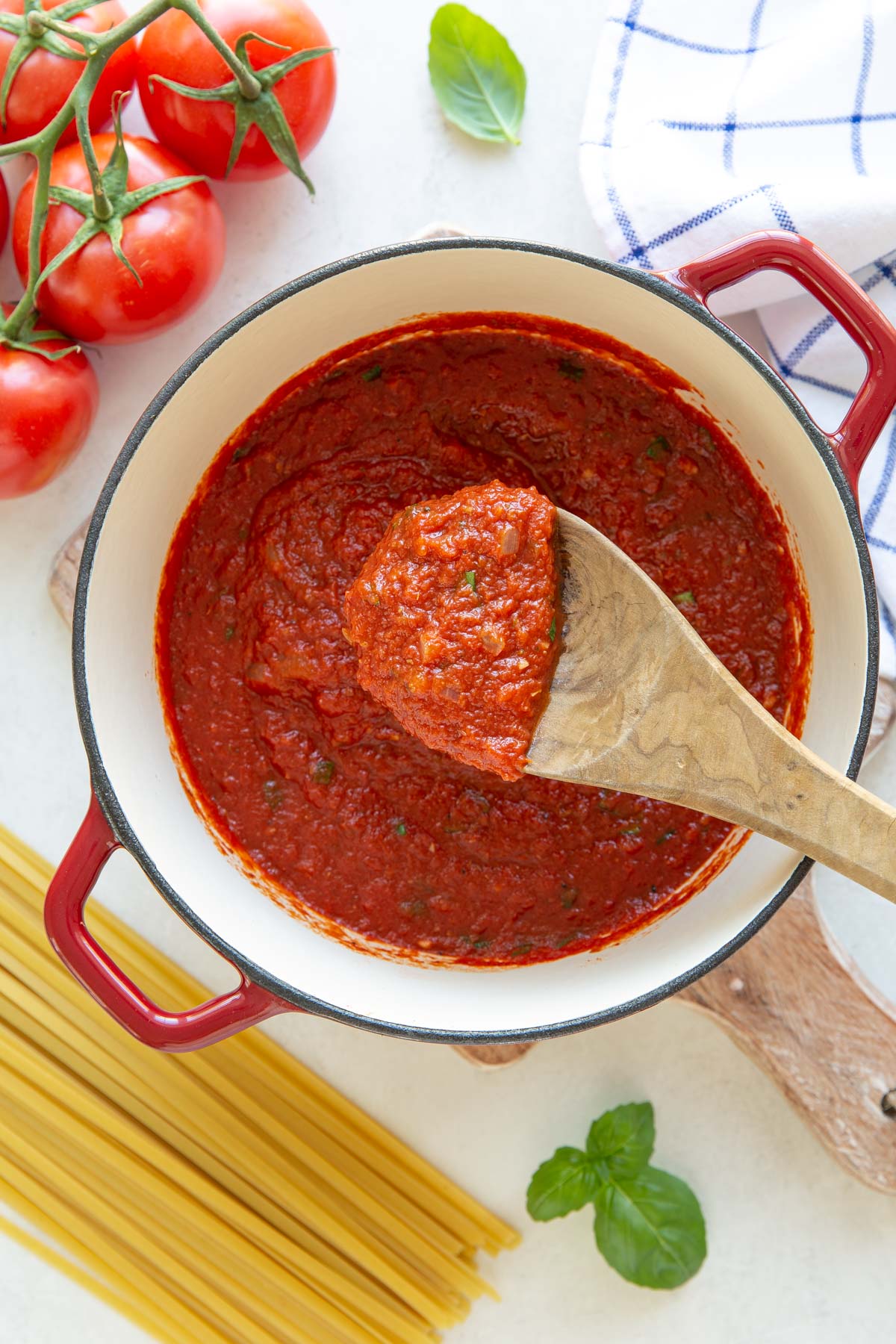 Overhead view of a wooden spoon in a pot of homemade marinara sauce.