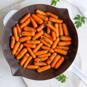 Overhead view of maple glazed baby carrots in a skillet.