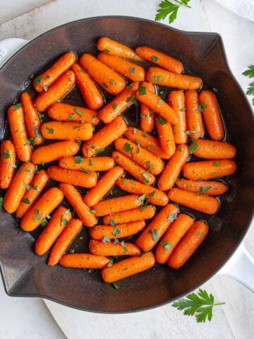 Overhead view of maple glazed baby carrots in a skillet.