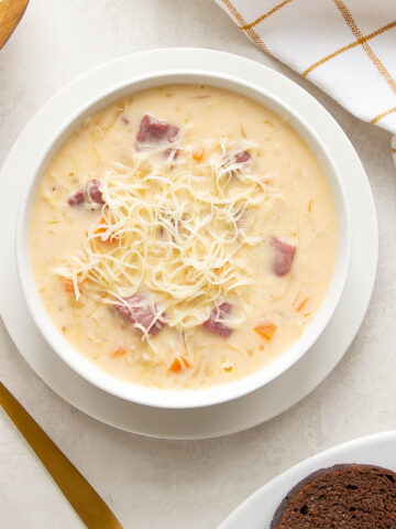 Overhead view of a bowl of creamy Reuben soup beside a gold spoon.