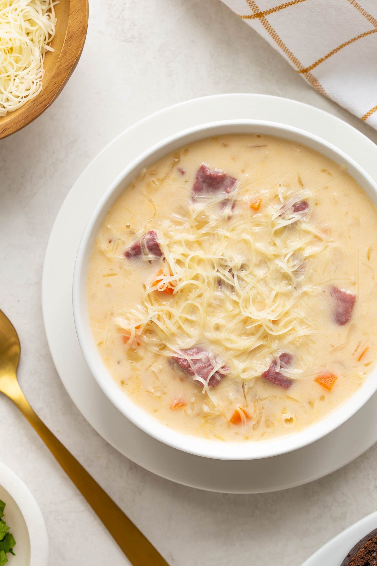 Overhead view of a bowl of Reuben soup topped with shredded Swiss cheese.