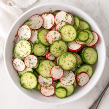 Overhead closeup view of cucumber radish salad in a white bowl.