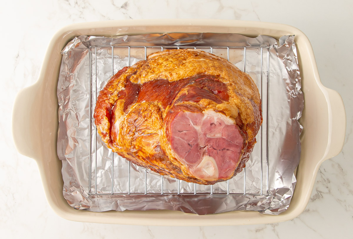 Overhead view of a spiral ham on a rack in a baking dish.