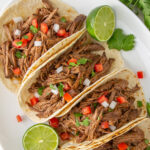 Shredded beef soft tacos on a platter with overlay text.