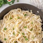 Fettucine with Alfredo sauce in a pan. Overlay text at top of image.