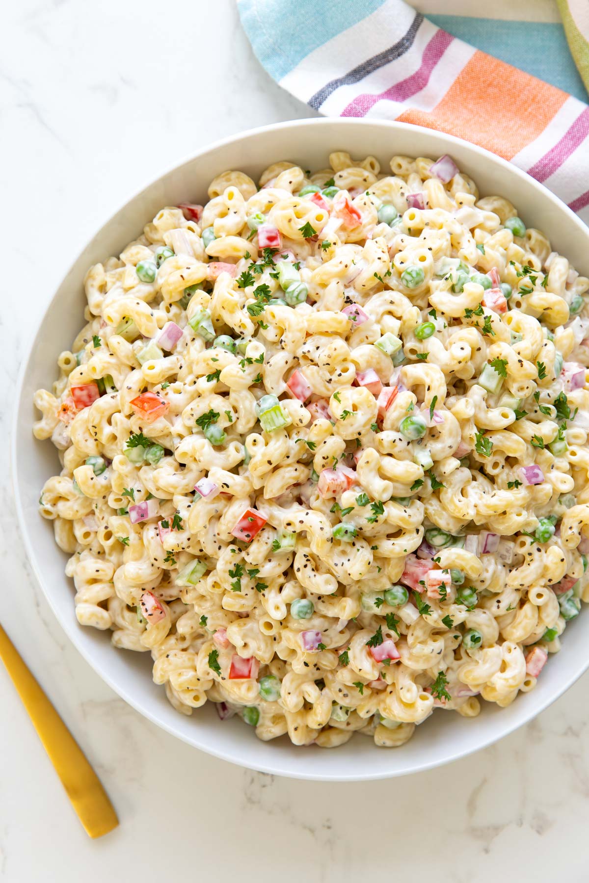 Overhead view of classic macaroni salad in a large white bowl.