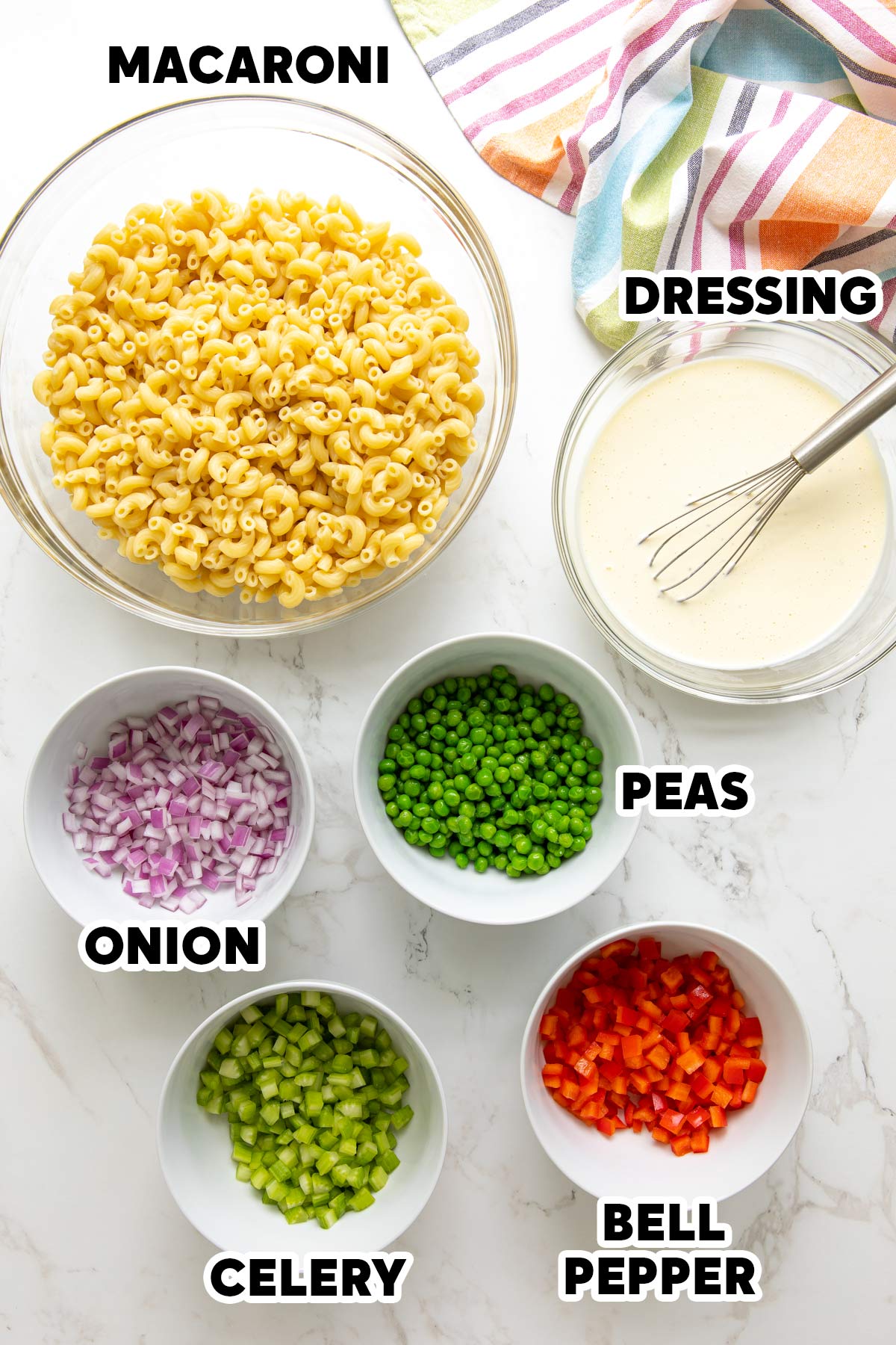 Overhead view of ingredients for macaroni salad with overlay text.