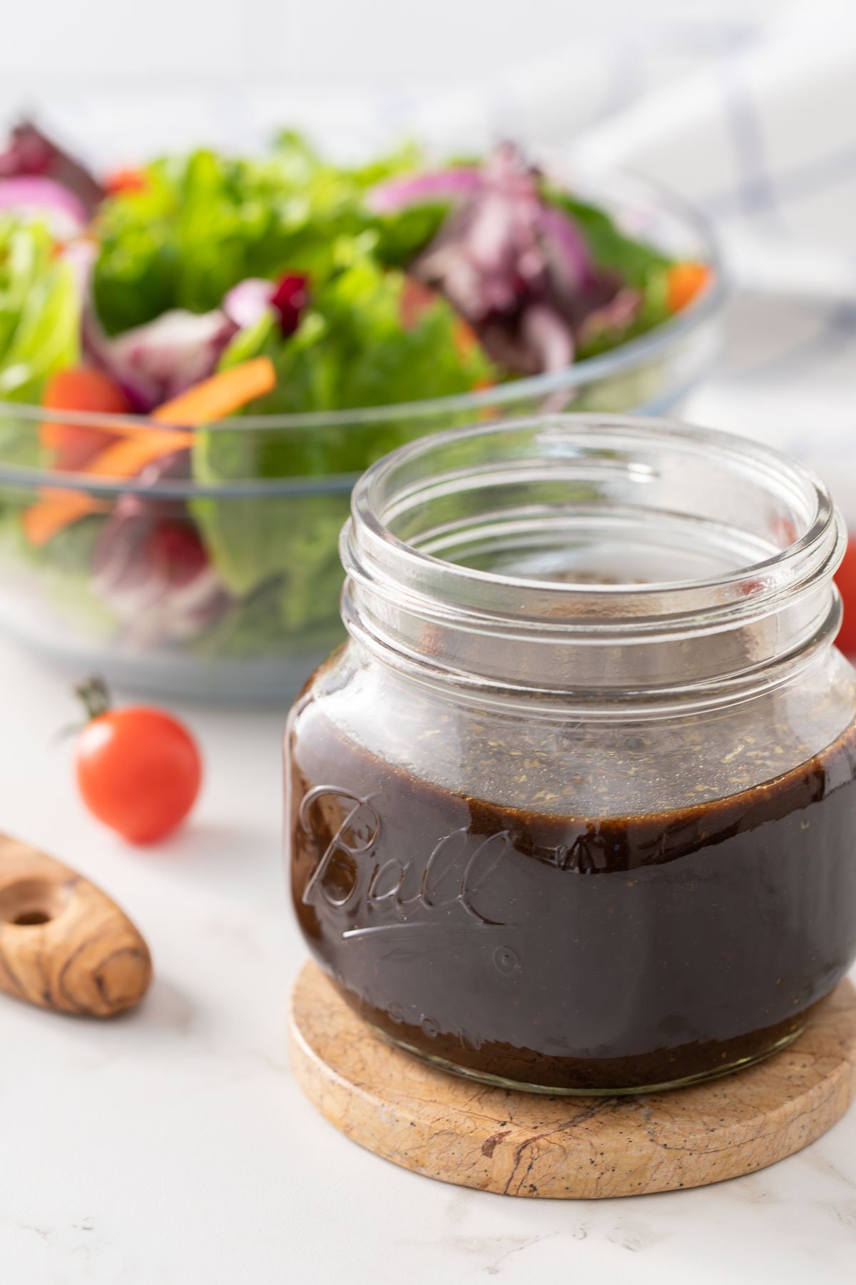 Homemade balsamic vinaigrette in a jar with a garden salad in the background.