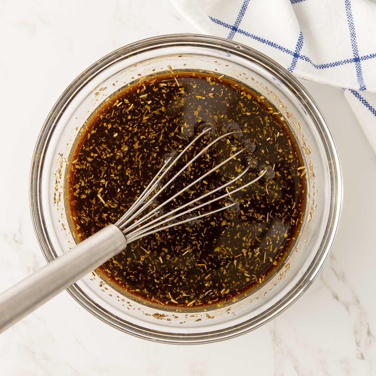 Overhead view of balsamic salad dressing in a bowl with a whisk.