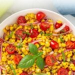 Overhead closeup view of a bowl of corn and tomato salad with overlay text.