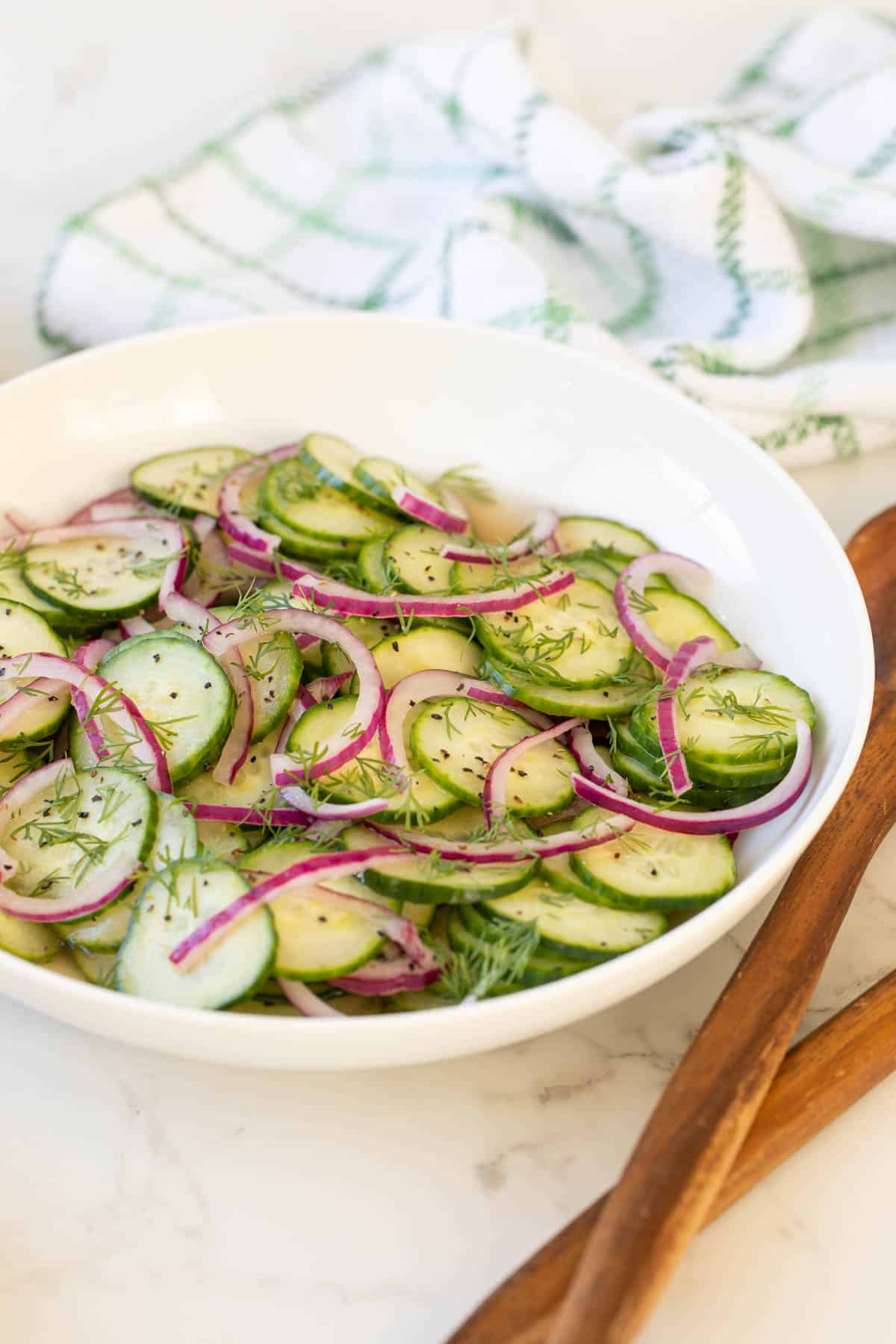 Front closeup view of cucumber and onion salad in a white bowl.