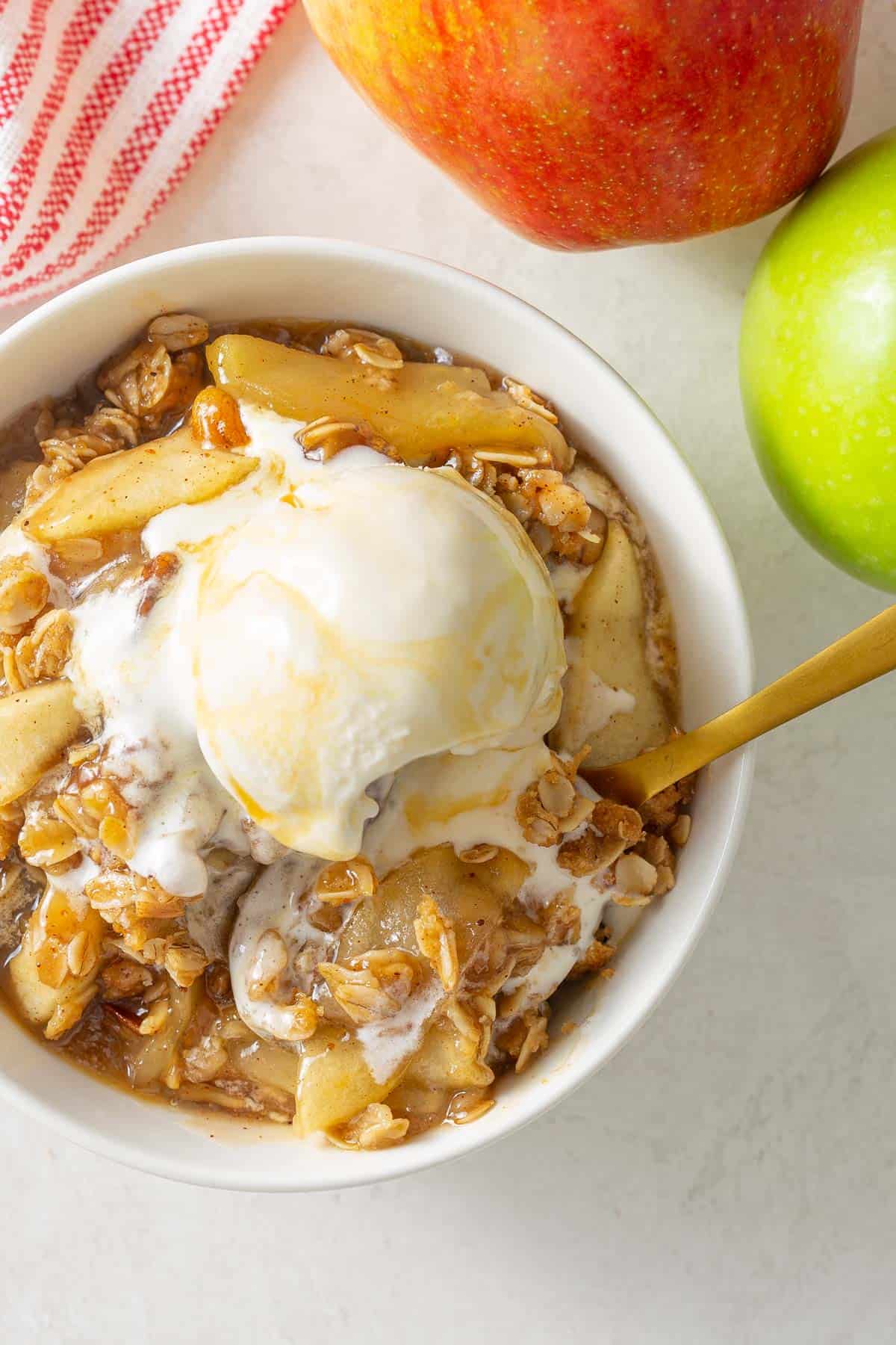 Overhead view of a spoon in a bowl of apple crisp.
