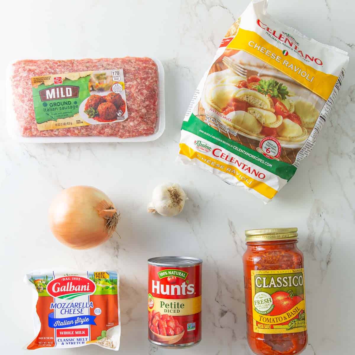 Ingredients for baked ravioli on a white marble surface.