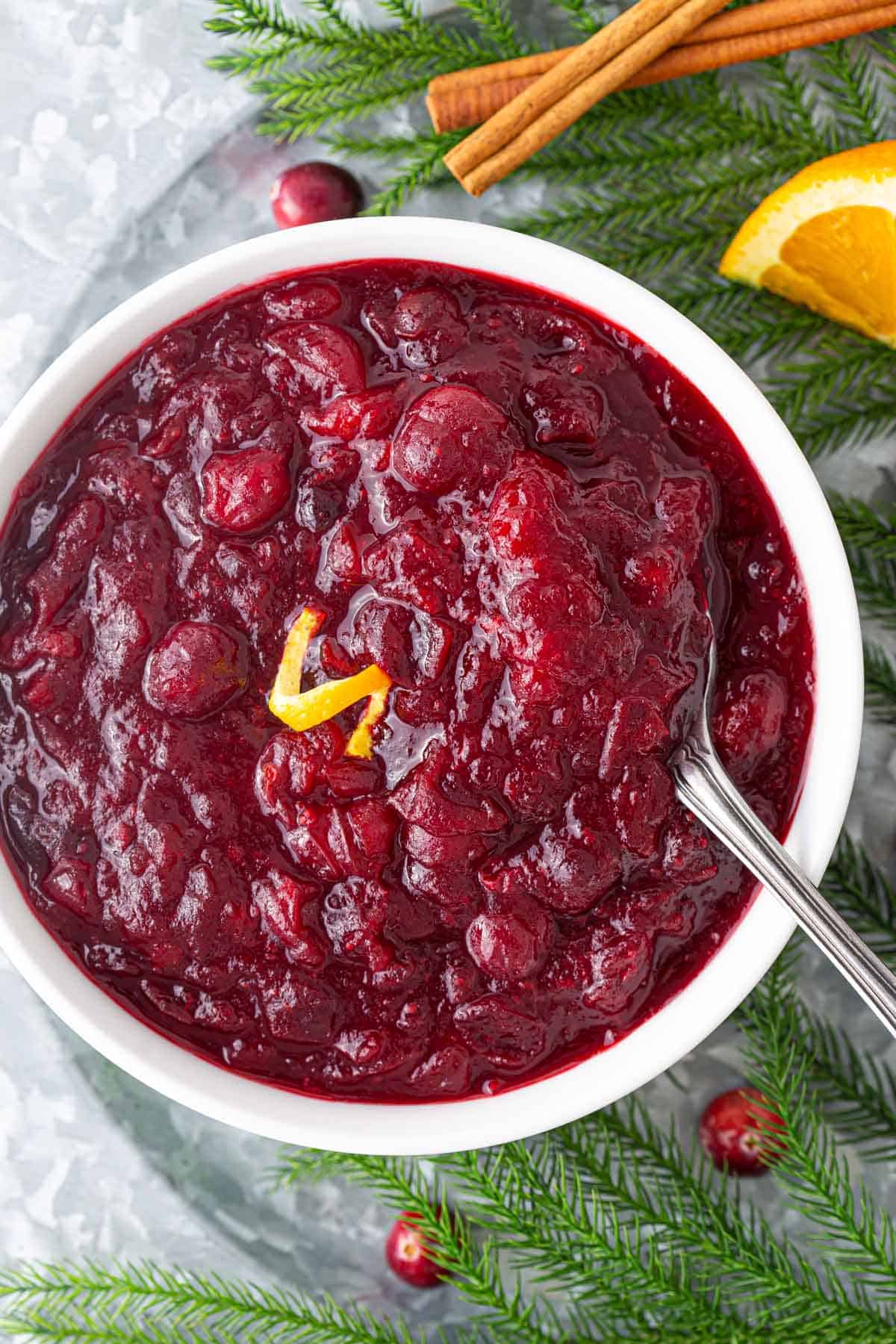 Overhead closeup view of cranberry sauce in a white bowl with a spoon.